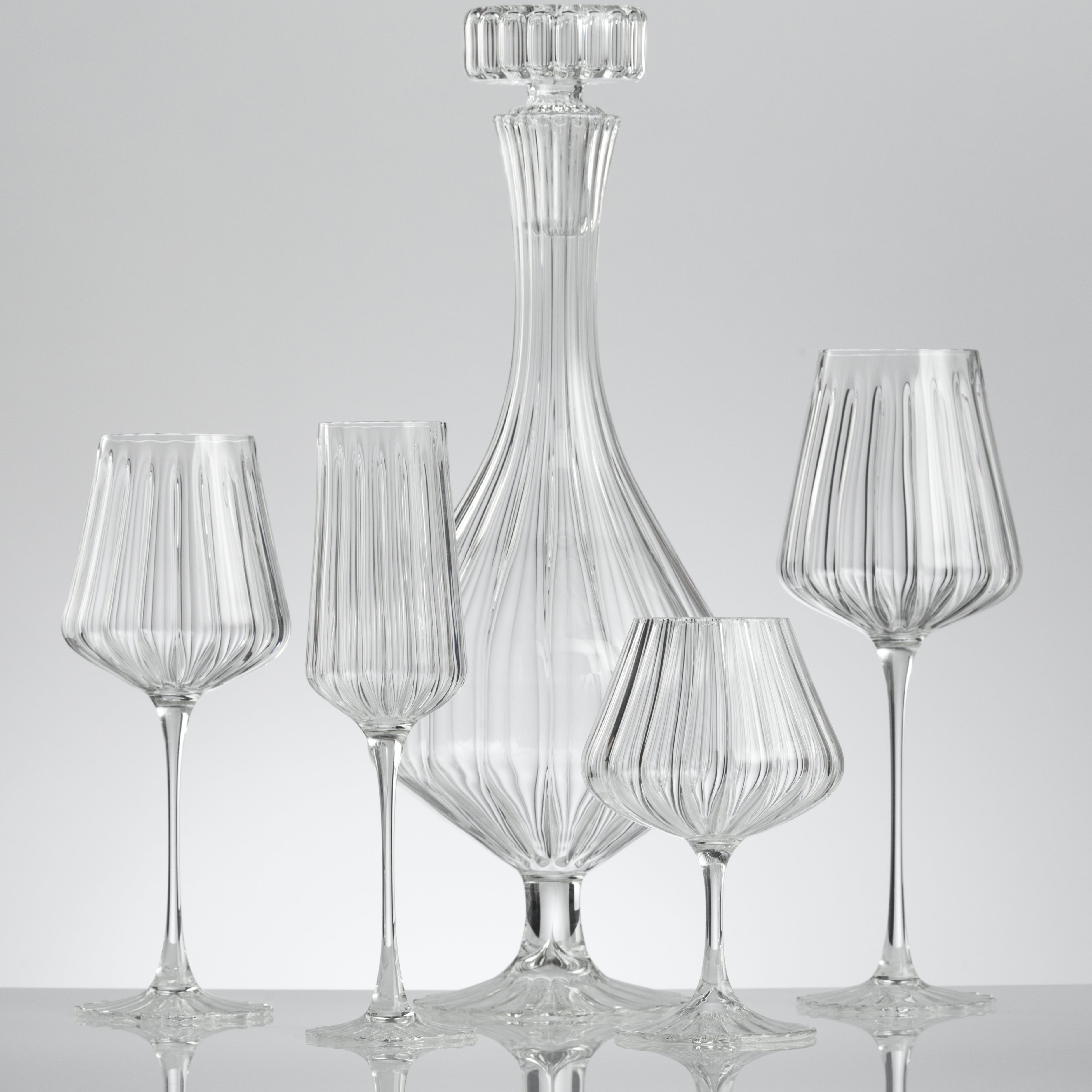 Lined glass used for Red Wine Glass, Champagne Glass, Cognac Glass and Red Wine Glass in front of a Carafe with Lid with a grey background