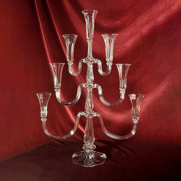 Clear glass candelabra against a red fabric background. Gabriela Seres designed candelabra handmade in Bucharest